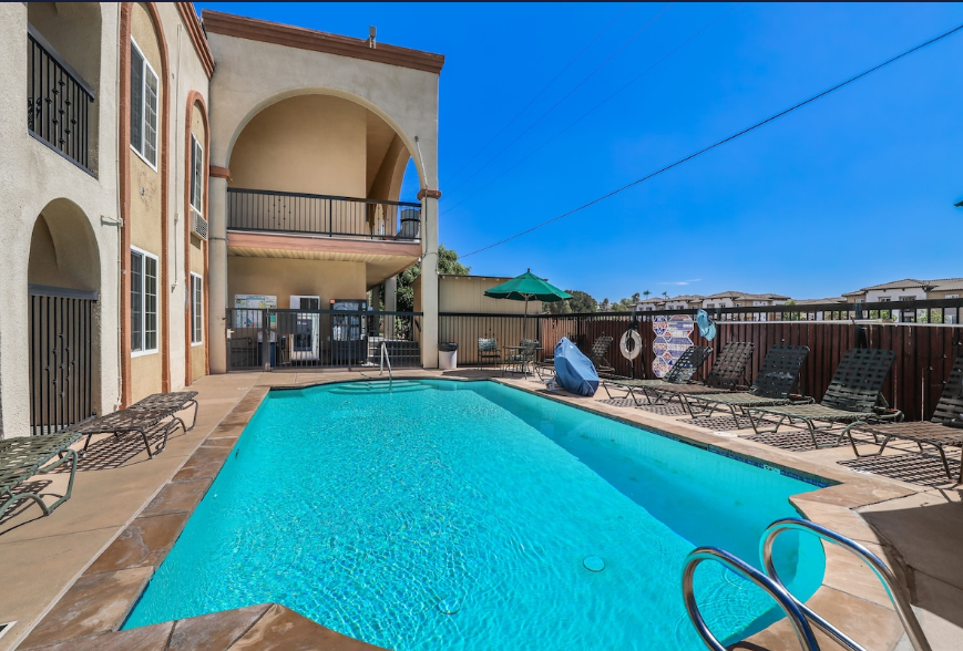 Outdoor pool framed by stucco arches and second-floor balcony of the motel