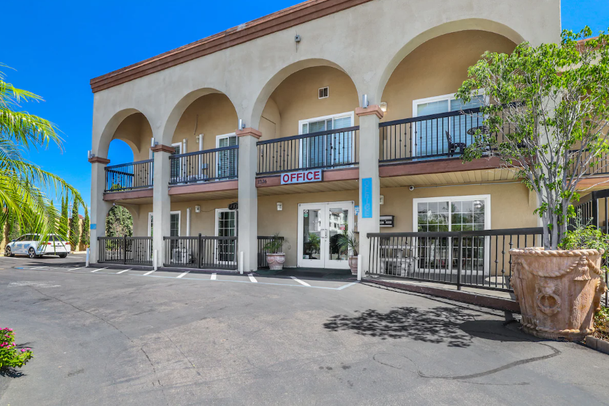 White stucco facade with arcaded balconies above the front office in daylight
