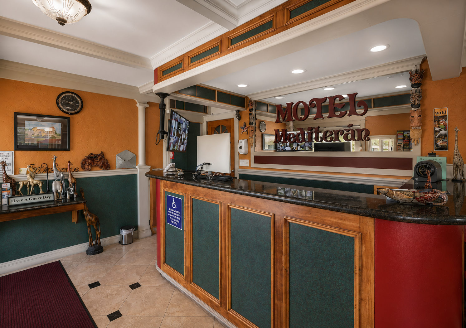 Front desk lobby with carved Motel Mediteran sign and warm orange walls