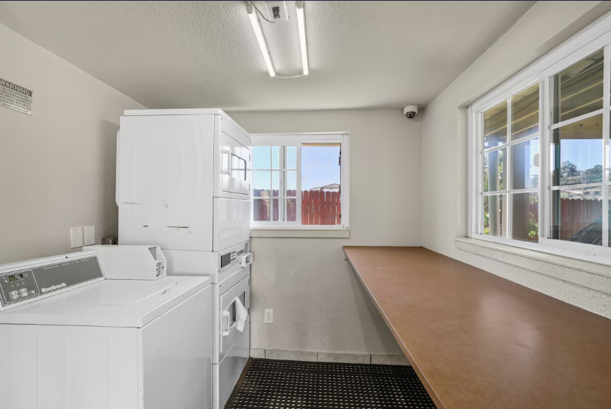 Bright self-service guest laundry room with washer, dryer, and folding counter